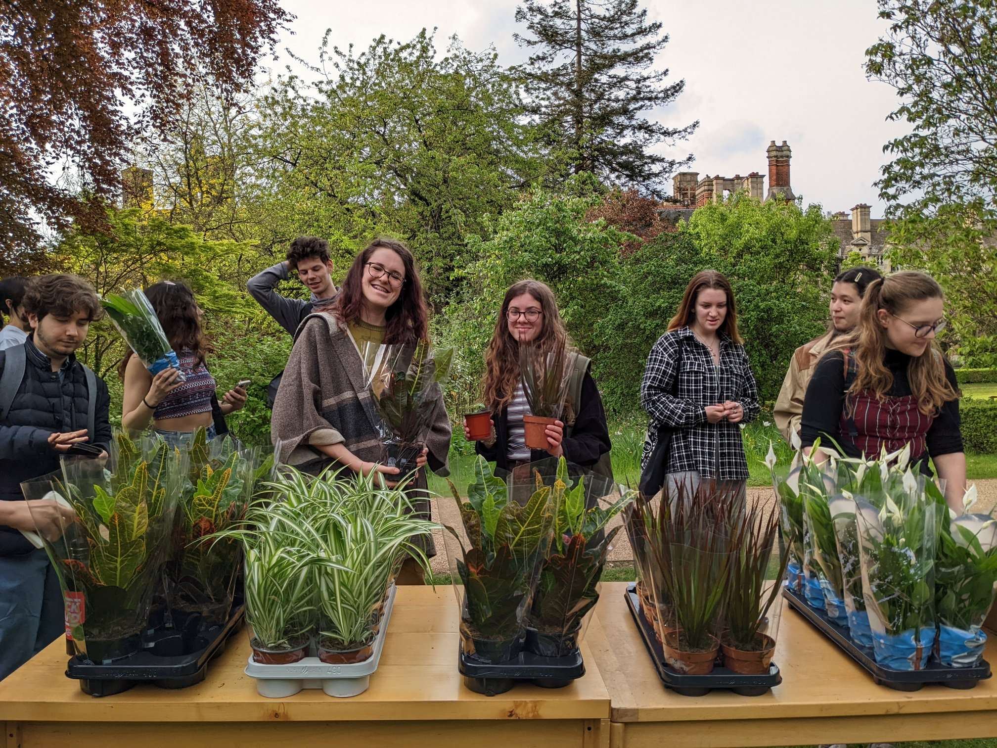 A table displaying plants. Students stand behind it, some with plants in hand. 