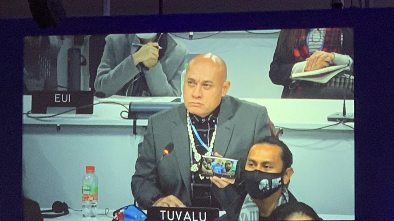 Tuvalu’s Minister of Finance Seve Paeniu holding up a photo of his grandchildren, urging countries to take action