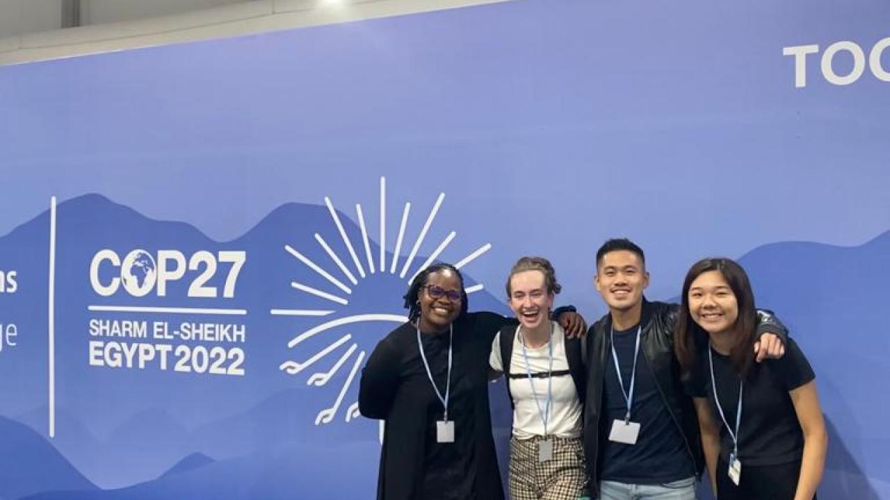 Laura and other youth participants in front of COP27 sign