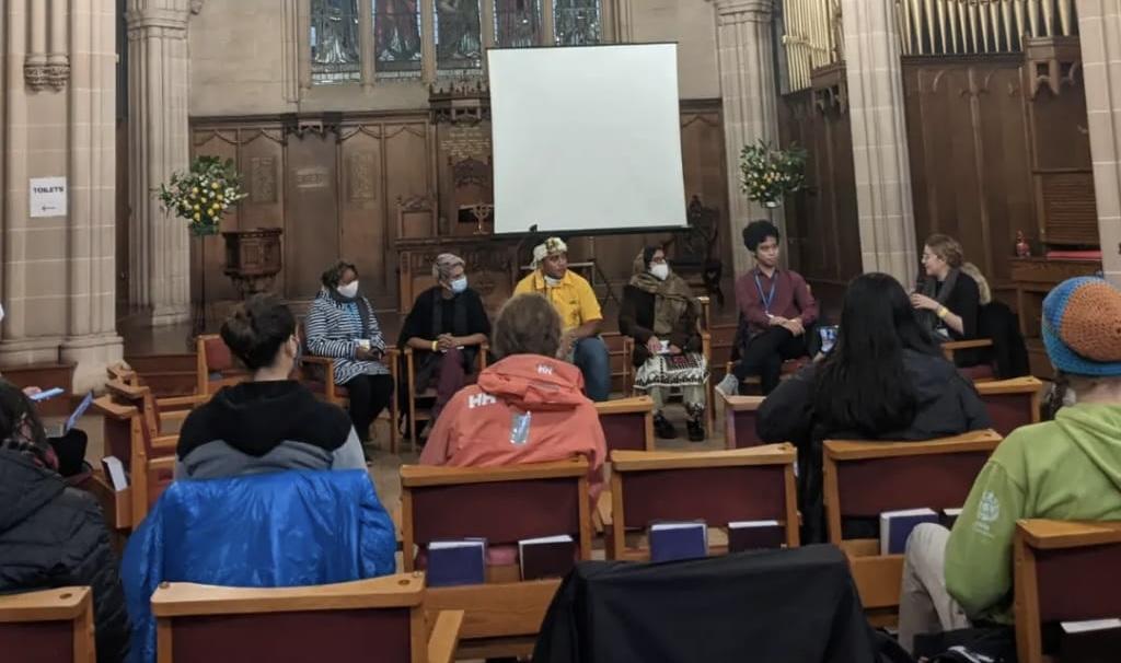 Young person from Tuvalu and others on a panel talk to an audience in a Church in Glasgow.