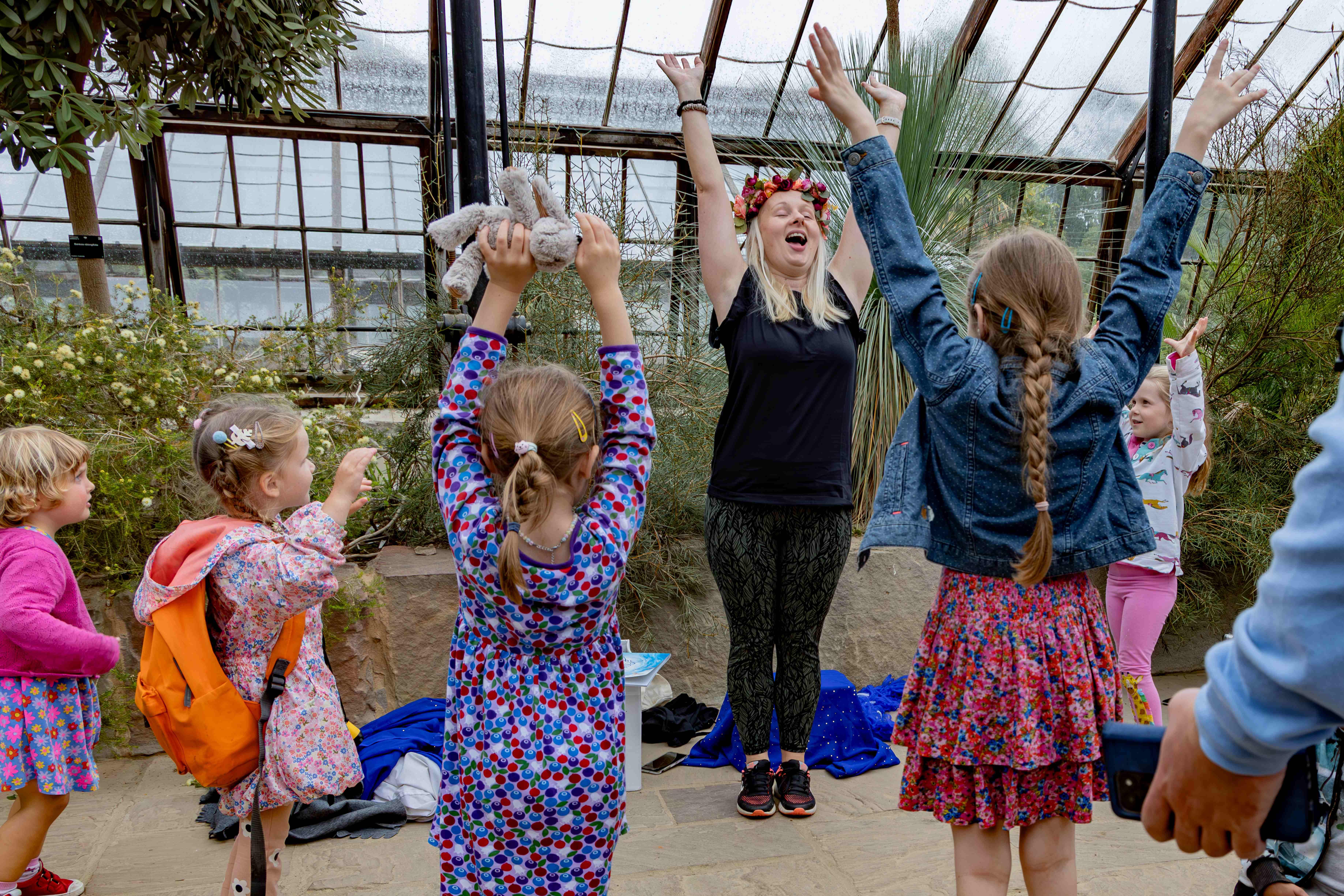 Children throw their arms up in the air at a Botanic Garden story-telling event
