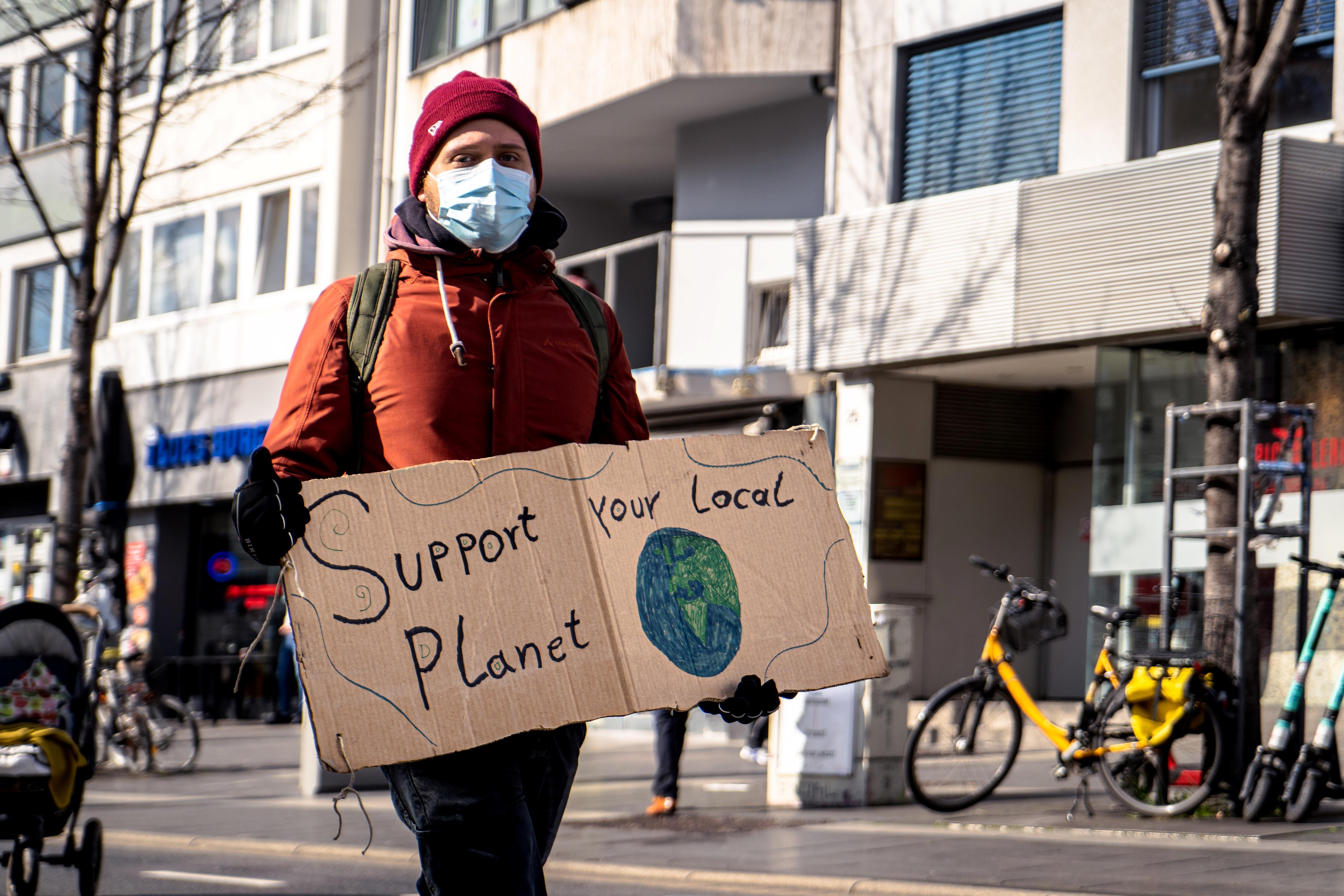 Protester carries placard saying "Support Planet"